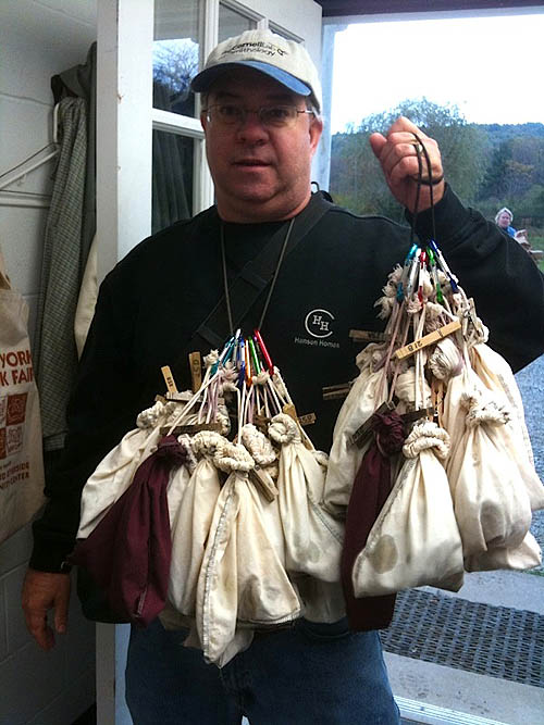 man holding approximately 10 cloth bags with birds in them