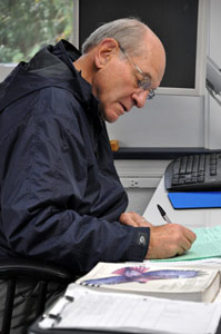 Older man writes at a desk